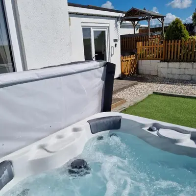 a hot tub in the backyard of a house at Hegarty's cottage at Trevarrian Lodge in Mawgan Porth