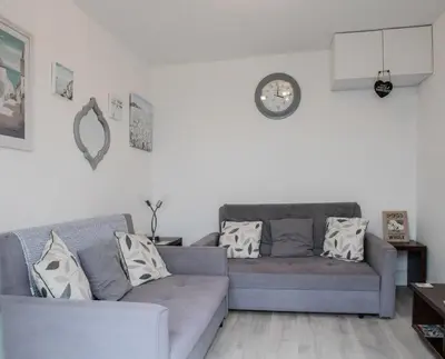 a living room with two couches and a clock on the wall at Hegarty's cottage at Trevarrian Lodge in Mawgan Porth