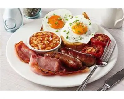 a plate of breakfast food with eggs sausage and beans at Trelawne Garden Annexe in Falmouth