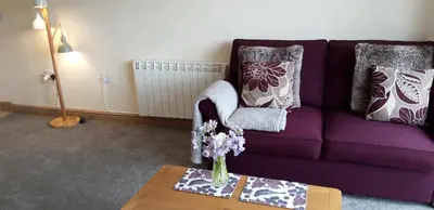a purple couch with a vase of flowers on a table at Trelawne Garden Annexe in Falmouth