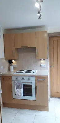 a kitchen with a stove and wooden cabinets at Trelawne Garden Annexe in Falmouth