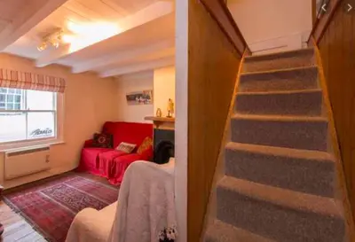a room with a staircase and a red couch at Jacobs Cottage in Port Isaac