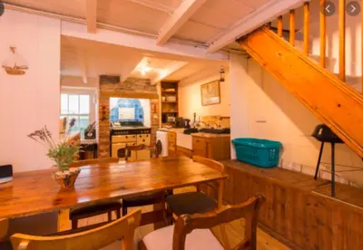 a dining room with a wooden table and a kitchen at Jacobs Cottage in Port Isaac