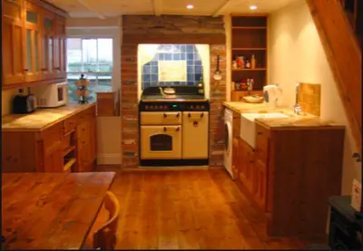a kitchen with a stove and a wooden floor at Jacobs Cottage in Port Isaac