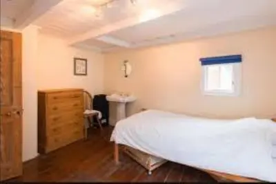 a bedroom with a bed and a dresser and a window at Jacobs Cottage in Port Isaac