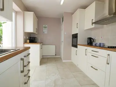 a kitchen with white cabinets and a tile floor at Garden View in Newquay