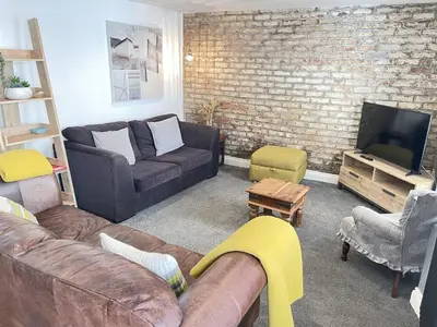 a living room with a couch and a tv at Treholme, great space for a family beach holiday! in St Ives