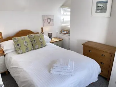 a bedroom with a white bed with a wooden head board at Treholme, great space for a family beach holiday! in St Ives