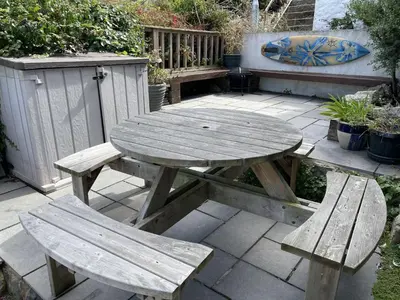 a wooden picnic table and two benches on a patio at Treholme, great space for a family beach holiday! in St Ives