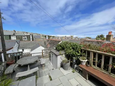 a balcony with a wooden table and a table at Treholme, great space for a family beach holiday! in St Ives