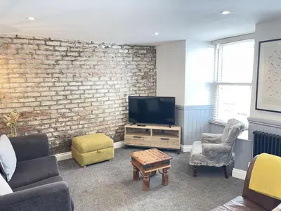 a living room with a tv and a brick wall at Treholme, great space for a family beach holiday! in St Ives