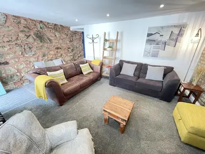 a living room with couches and a stone wall at Treholme, great space for a family beach holiday! in St Ives