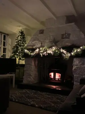 a living room with a stone fireplace with a christmas tree at Lime Kiln Cottage, Pentewan, Cornwall in Pentewan