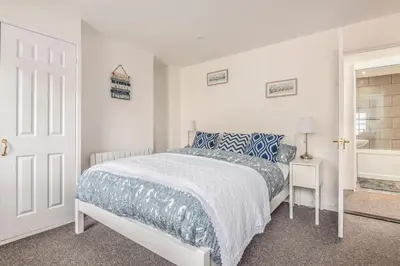 a white bedroom with a bed and a bath tub at Lime Kiln Cottage, Pentewan, Cornwall in Pentewan