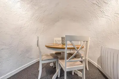 a table and two chairs sitting next to a white wall at Lime Kiln Cottage, Pentewan, Cornwall in Pentewan