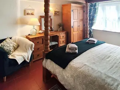 a bedroom with a bed and a dresser and a window at Laity in Polperro