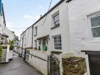 a white house with a gate on a street at Talland House in Polperro