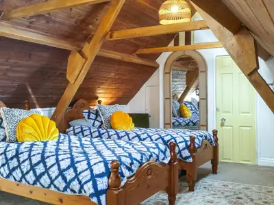 a bedroom with a bed with a blue and yellow comforter at Talland House in Polperro