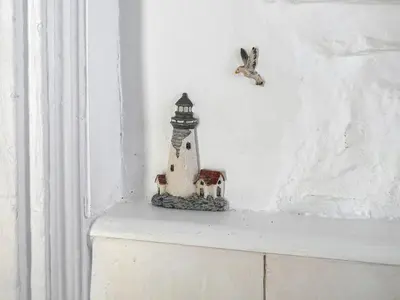 a small lighthouse figurine sitting on top of a shelf at Talland House in Polperro