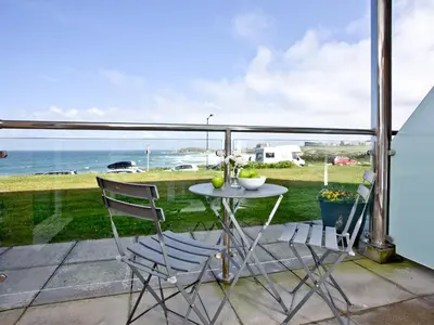 a table and two chairs on a balcony with the ocean at Apartment 2 Waters Edge in Crantock