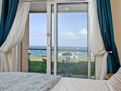 a bedroom with a bed and a view of the ocean at Apartment 2 Waters Edge in Crantock