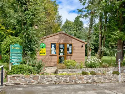 a small building with a sign in front of it at Forest Glade Lodge in Lanlivery