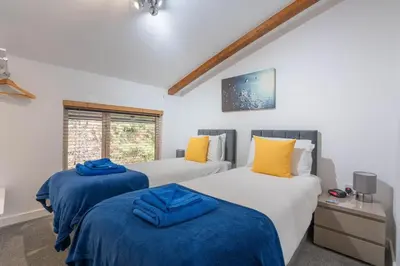 a bedroom with two beds with blue and yellow sheets at Cornish Holiday - Bodannon in Porthtowan