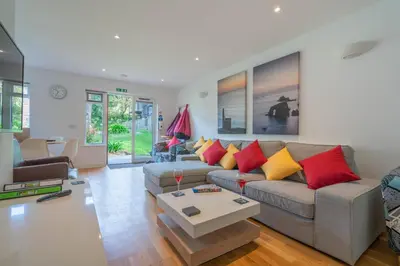 a living room with a gray couch with red and yellow pillows at Cornish Holiday - Bodannon in Porthtowan
