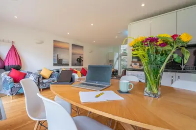 a dining room table with two laptops and flowers on it at Cornish Holiday - Bodannon in Porthtowan