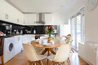 a kitchen with a wooden table and white chairs at Cornish Holiday - Bodannon in Porthtowan