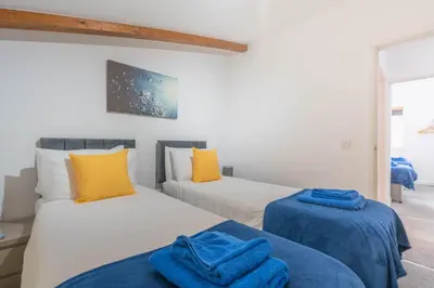 two beds in a room with yellow and blue at Cornish Holiday - Bodannon in Porthtowan