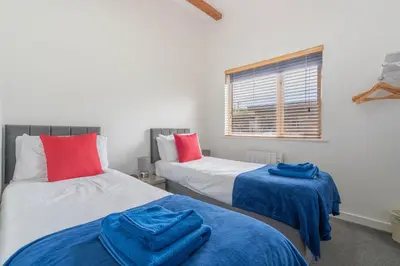 a bedroom with two beds with blue sheets and a window at Cornish Holiday - Bodannon in Porthtowan