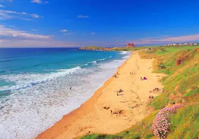 a beach with people on the sand and the ocean at The Black Palms - Fistral Beach in Newquay