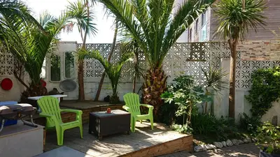 a patio with two green chairs and palm trees at The Black Palms - Fistral Beach in Newquay