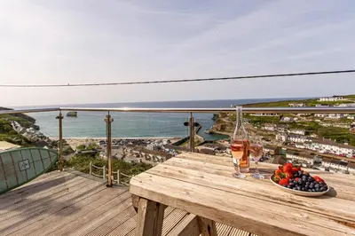 a table with a bowl of fruit and a glass of wine at Sea views, Cornwall, Portreath, hot tub, sauna in Portreath
