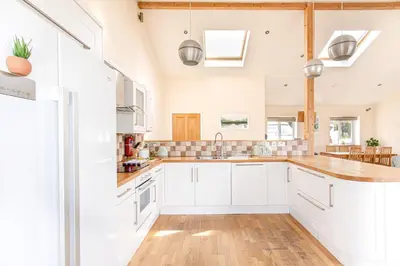 a kitchen with white cabinets and a wooden floor at Sea views, Cornwall, Portreath, hot tub, sauna in Portreath