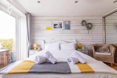 a bedroom with a large white bed with two pillows at Sea views, Cornwall, Portreath, hot tub, sauna in Portreath