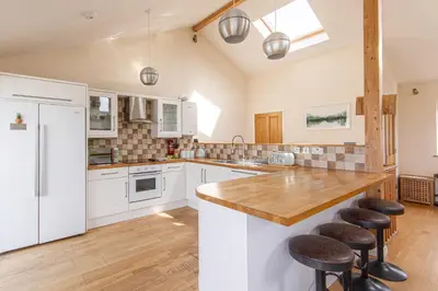 a kitchen with white cabinets and a wooden counter top at Sea views, Cornwall, Portreath, hot tub, sauna in Portreath