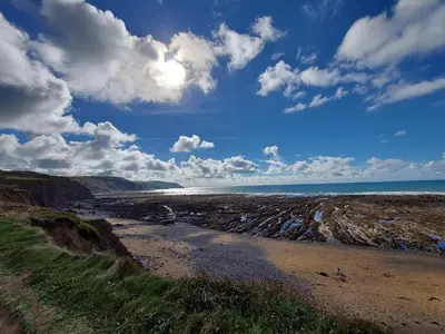 a beach with the ocean and a cloudy sky at Chalet 26 Widemouth Bay in Bude