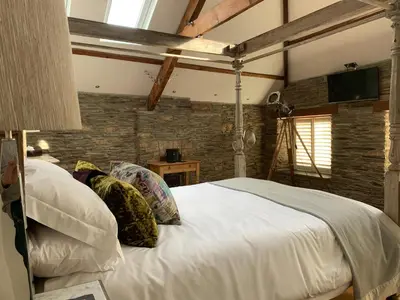 a bedroom with a large white bed and a brick wall at The Padstow Cottage - Coswarth House in Padstow