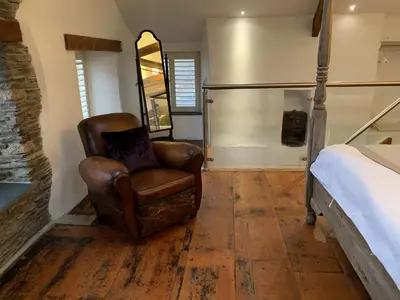 a bedroom with a leather chair and a bed at The Padstow Cottage - Coswarth House in Padstow