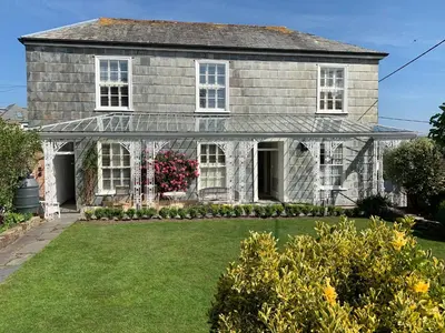 an old house with white windows and a yard at The Padstow Cottage - Coswarth House in Padstow