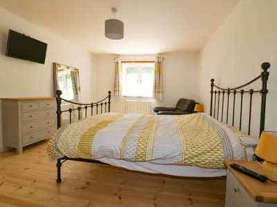 a bedroom with a bed with a desk and a chair at The Cart House in St Austell