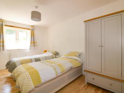 a bedroom with two beds and a cabinet at The Cart House in St Austell