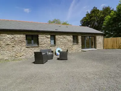 a stone house with two chairs in front of it at The Cart House in St Austell