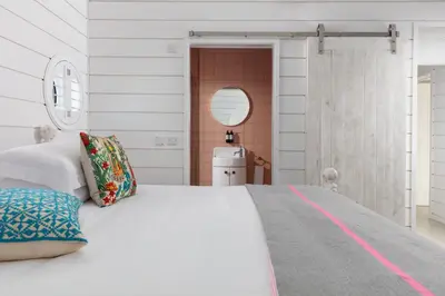a bedroom with a large white bed and a mirror at Three Mile Beach in Hayle