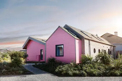 a pink house in front of a white house at Three Mile Beach in Hayle