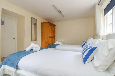 two white beds in a room with a window at 9 Copes Gardens in Truro