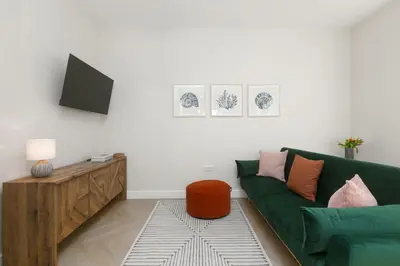 a living room with a green couch and a tv at White Waves in St Ives