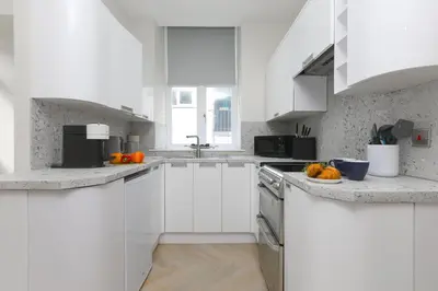 a white kitchen with white cabinets and oranges on the counter at White Waves in St Ives